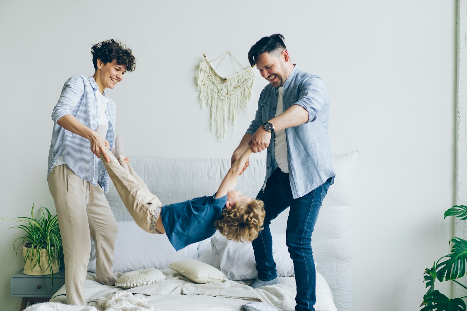 A man and a woman playing with a child on a bed