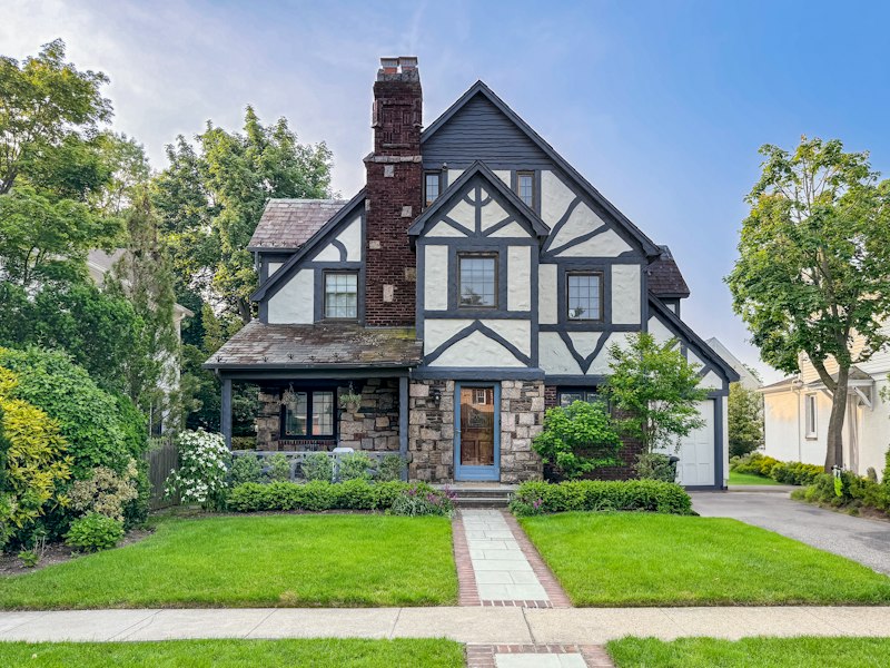 A charming tudor-style home with a beautiful yard